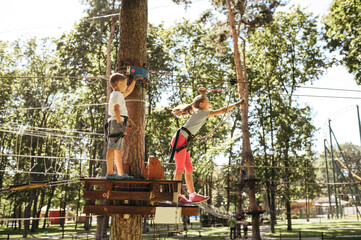 Wall Mural - Little funny kids climbs on net in rope park