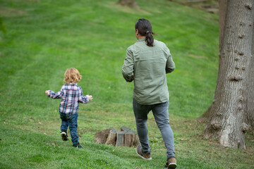 Child and father playing in the green grassy park on a sunny day