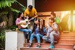 © StockImageFactory - Indian asian university student singing song with guitar in college campus and friends enjoying