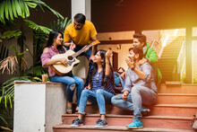 Indian Asian University Student Singing Song With Guitar In College Campus And Friends Enjoying