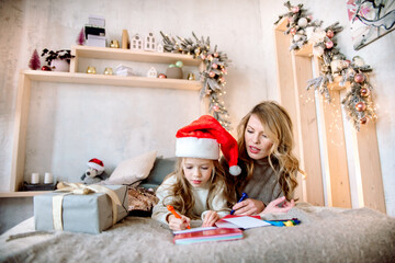 Mom and daughter are writing a letter to Santa. christmas at home