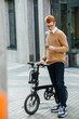 © zzzdim - Busy handsome young man with ebike and phone on the street.