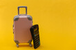 © splitov27 - Travel expenses. Mini pink plastic travel suitcase with calculator on yellow background. Minimal style
