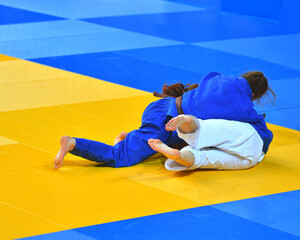 Two Girls judoka in kimono compete on the tatami 