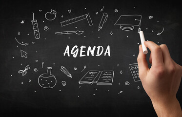 Hand drawing AGENDA inscription with white chalk on blackboard, education concept