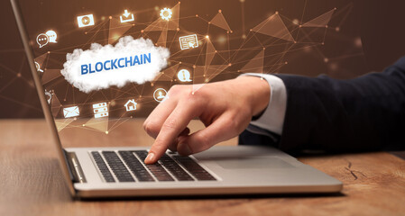 Businessman working on laptop with BLOCKCHAIN inscription, modern technology concept