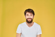 © SHOTPRIME STUDIO - Bearded man white t-shirt emotions gestures with hands fun yellow background
