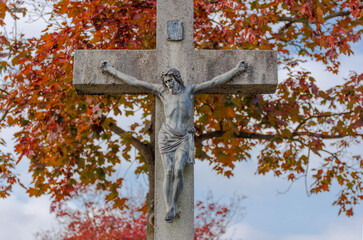 Old statue of Jesus Christ on the cross in autumn. Crucifixion, religion and spirituality