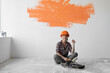 © Andrii Lysenko - happy woman sits on the floor with orange spot on the wall. home renovation concept