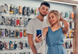 © Olena Apetroaiei - Close up focus view of a stylish charming embracing young student love couple taking a selfie with new mobile in a tech store.