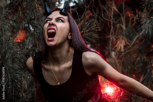 woman on Halloween shows the inner demon. scream of evil in the street. exorcising the devil in the forest. with horns possessed by the devil, Halloween makeup. occultism, mysticism, religion, evil