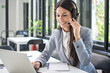 © Bojan - Smiling business woman with headset using laptop in office