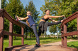 © Андрей Рыков - Mother and daughter stretching legs together on top of wooden staircase in public park on sunny summer morning. Family outdoor sports theme.
