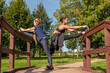 © Андрей Рыков - Mother and daughter stretching legs together on top of wooden staircase in public park on sunny summer morning. Family outdoor sports theme.