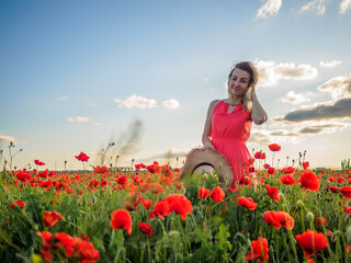 Young girl in a red dress in a poppy field
