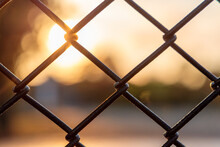 Sunset Through Chain Link Fence With Blue Sky