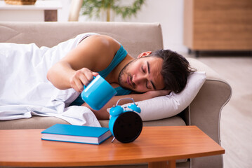 Wall Mural - Young man lying on the sofa in time management concept