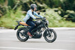 © DragonImages - Young Asian man concentrated on road when riding fast on highway