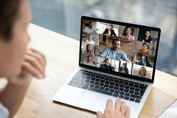 Close up rear view of person talk speak on video call with multiracial diverse colleagues. Employee have webcam team online meeting or group digital briefing on computer with multiethnic coworkers.