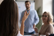 © fizkes - Crop close up of confident female employee raise hands ask answer question at business meeting in office. Woman volunteer interact with coach, participate in team group discussion at briefing.