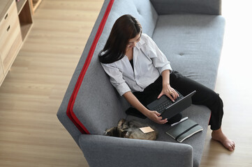 Wall Mural - Asian woman using tablet and relax time lying on home sofa in living room at home.