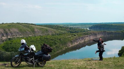 Wall Mural - Loving couple, family of extreme travelers. On top and enjoy a beautiful view of the mountains and the river. Motorcycle with bags and a tent. Motobike for long trips. Ukraine