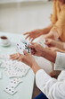 © DragonImages - Hands of senior women playing cards and drinking tea when spending weeend together