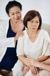 © DragonImages - Senior Asian women reassuring their frustrated friend, touching her hands and patting on shoulder