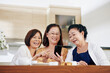 © DragonImages - Group of cheerful Vietnamese senior women watching funny videos on smartphone screen
