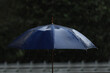 © bahadirbermekphoto - Raindrops falling on a blue umbrella on a rainy day. Blurred background