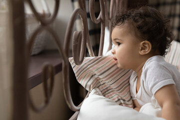 Wall Mural - close up of curious little african american baby infant kid stand sit on cozy comfortable bed at hom