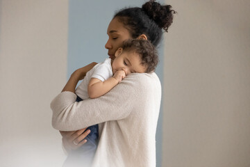 Wall Mural - loving young biracial mother hold in hands embrace small newborn baby child. caring african american