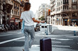 © Rymden - Young traveling woman with suitcase on a sunny city street. Traveler on vacation. Waiting for taxi