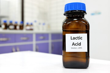 Wall Mural - Selective focus of lactic acid liquid solution in dark brown glass bottle in a white chemistry laboratory background. Chemical peel for skincare research.