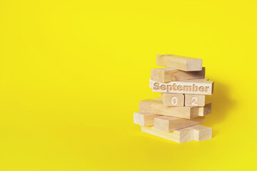 September 2nd. Day 2 of month, Calendar date. Wooden blocks folded into the tower with month and day on yellow background, with copy space. Autumn month, day of the year concept.