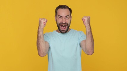 Wall Mural - Handsome bearded young man 20s in basic casual blue t-shirt isolated on yellow background studio. People lifestyle concept. Waiting for special moment worried making wish doing winner gesture say Yes