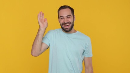 Canvas Print - Calm happy smiling bearded young man 20s in basic casual blue t-shirt sleeping on folded hands wake up stretching waving greeting isolated on yellow background studio. People emotion lifestyle concept