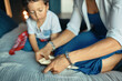 © Anatoliy Karlyuk - Portrait of curious dark skinned little boy sitting on bed watching his mother making origami, folding paper. Creativity, early development, hobby and leisure. Selective focus on woman’s hands
