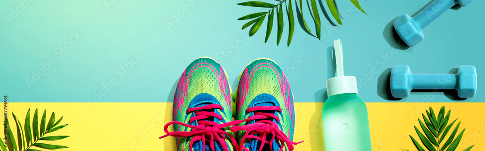 Fitness shoes and dumbbells with tropical plants - flat lay - obrazy, fototapety, plakaty 