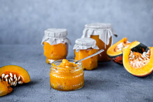 Homemade Pumpkin Jam In Glass Jars On Grey Stone Table. Copy Space.