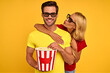 © Roman - Laughing couple two friends guy girl in 3d glasses isolated on yellow background. People in cinema lifestyle concept. Watching movie film holding bucket of popcorn, hugging, kiss in cheek