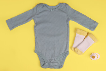 Wall Mural - Newborn baby clothing bodysuits and socks on a bright background