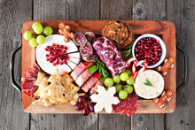 Christmas Theme Charcuterie Board. Above View Against A Dark Wood Background. Variety Of Cheese And Meat Appetizers.