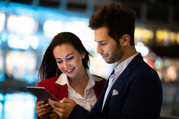 Poster - Couple of business people using a tablet outdoor at night in a modern city setting