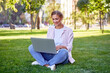 © Andrii - Businesswoman sitting grass summer park using laptop Business persone working remote. Outdoors