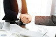 © Iryna - Unknown diverse business people are shaking hands finishing contract signing in sunny office, close-up. Business handshake concept