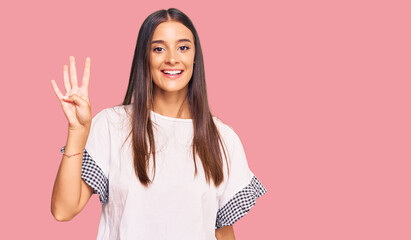 Wall Mural - Young hispanic woman wearing casual clothes showing and pointing up with fingers number four while smiling confident and happy.