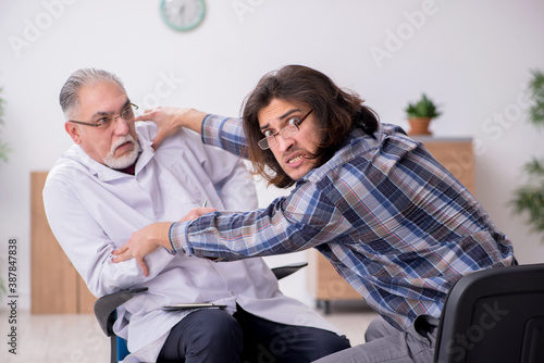 Fotografía Young male psychopath and experienced doctor in madhouse