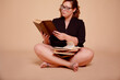 Fat woman in glasses holding books isolated on biege background