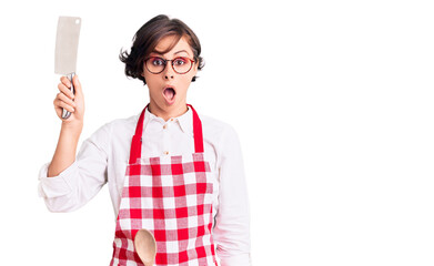 Sticker - Beautiful young woman with short hair wearing professional baker apron holding knife scared and amazed with open mouth for surprise, disbelief face